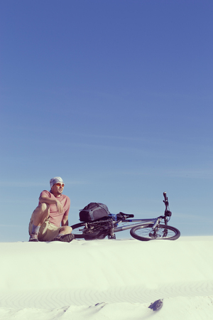 Travel by bike in the desert with a backpack and tent.の写真素材