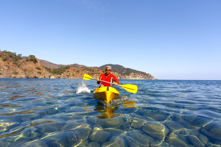 A man traveling by canoe along the coast in the summer.の写真素材