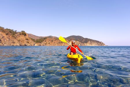 A man traveling by canoe along the coast in the summer.の写真素材