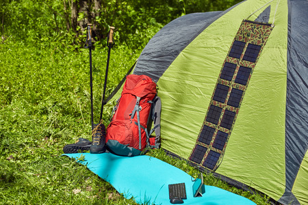 Camping in the forest with a tent, a backpack and a solar panel.の写真素材