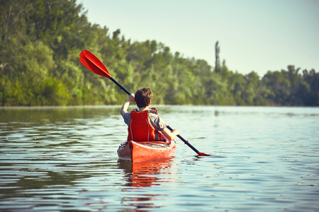 Boy on the river on kayaks on a sunny day.