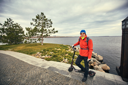 Athletic man with a backpack on the street with kick scooter.の写真素材