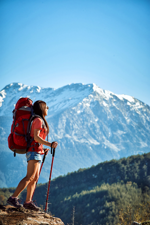Hike in the high mountains with a red backpack in the summer.の写真素材