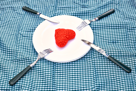 Installation of a table for Valentine's Day - plate forks and red hearts on a plate Love Romance.の写真素材