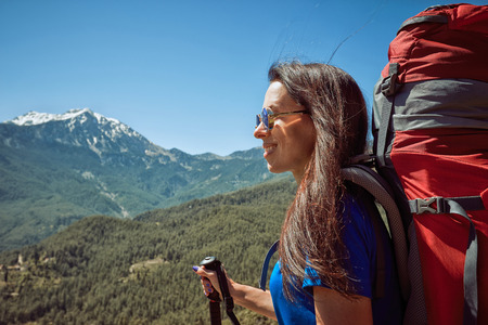 Hike in the high mountains with a red backpack in the summer.の写真素材