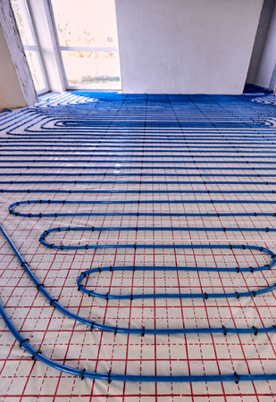 Laying blue pipes for floor heating at the construction site.の写真素材