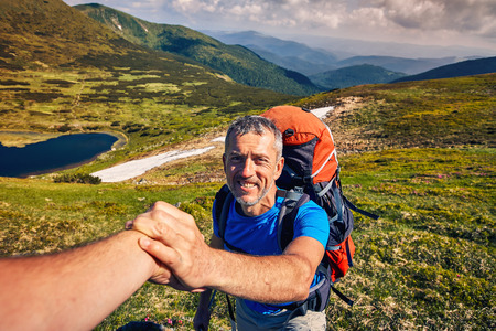 A helping hand for a girl high mountains in a hike.の写真素材