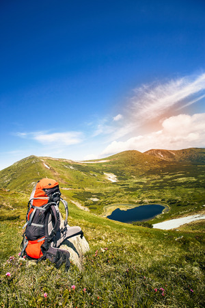 Summer hike in the mountains with a backpack and tent along the path to the top.の写真素材
