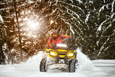 A man is riding an ATV in winter on the snow in his helmet.の写真素材