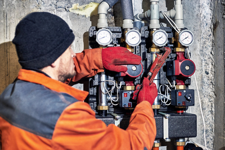 Plumber worker repairs the heating system in the house.の写真素材