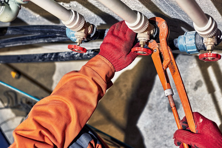 Plumber worker repairs the heating system in the house.