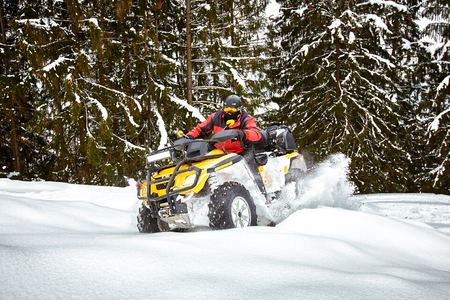 A man is riding an ATV in winter on the snow in his helmet.の写真素材