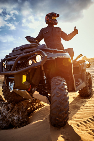 Racing powerful quad bike on the difficult sand in the summer.の素材 [FY310122138466]