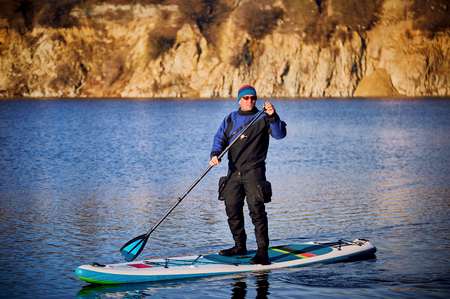 Men swim on the SUP boards in the rays of the rising sun.