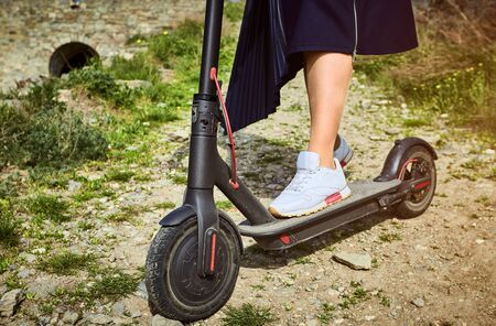 Using an electric scooter as a means of transportation on the street.