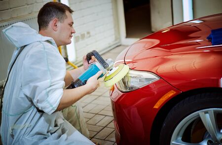 Polishing a red car on a customer service.の写真素材