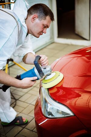 Polishing a red car on a customer service.の写真素材