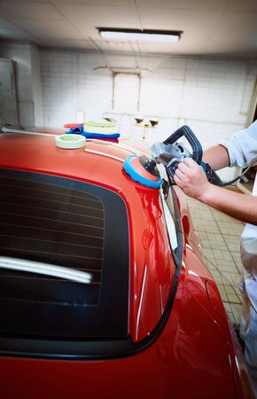 Polishing a red car on a customer service.の写真素材
