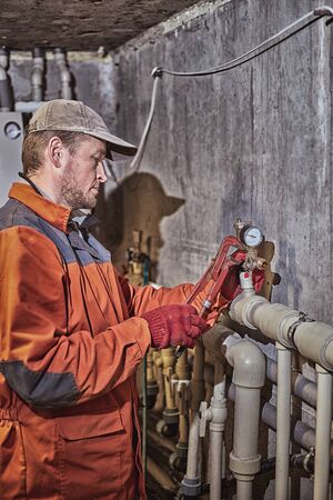 Plumber worker repairs the heating system in the house.の写真素材