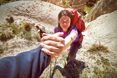 A helping hand for a girl high mountains in a hike.の写真素材