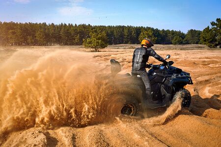 Racing powerful quad bike on the difficult sand in the summer.の写真素材