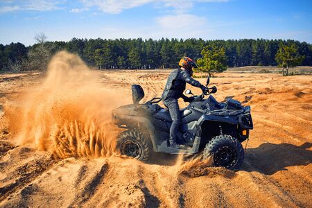 Racing powerful quad bike on the difficult sand in the summer.の写真素材
