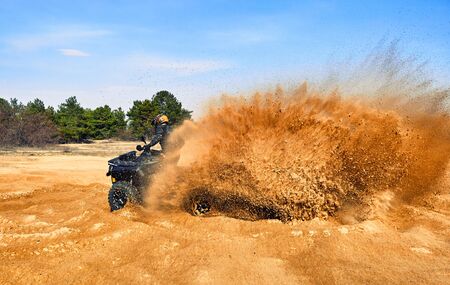 Racing powerful quad bike on the difficult sand in the summer.の写真素材