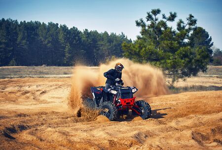 Racing powerful quad bike on the difficult sand in the summer.の写真素材