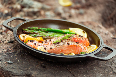 Healthy baked salmon steaks with greens and asparagus in a black cast iron skillet. A delicious low-carb breakfast.の写真素材