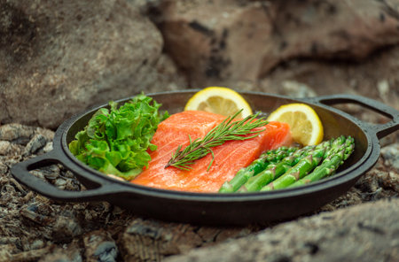 Healthy baked salmon steaks with greens and asparagus in a black cast iron skillet. A delicious...