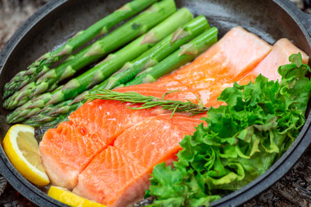Healthy baked salmon steaks with greens and asparagus in a black cast iron skillet. A delicious low-carb breakfast.の写真素材