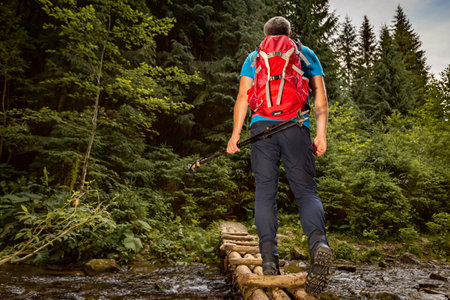 Hiking in mountainous terrain with a backpack and trekking poles.の写真素材