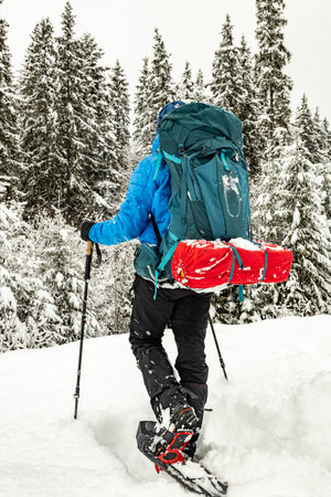 Winter hiking in the mountains with a backpack and snowshoes.の写真素材