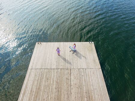 Aerial view . Two girls sing on the pier. Surrealism