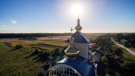 Aerial view of a new modern church with a blue tiled roof on a summer evening in a small village.の写真素材