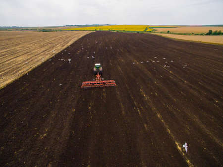 Harvesting in the field. Aerial view. Land cultivation with a tractorの写真素材