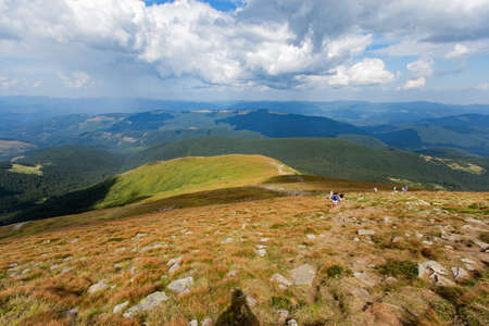 White clouds on a Blue sky over a large green meadow. High green mountainの写真素材