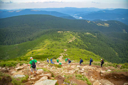 People descend down a large green mountain range. Mountain Hikingの写真素材