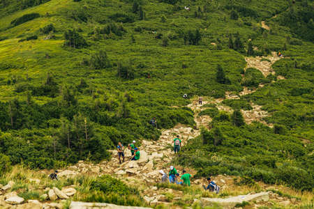 People descend down a large green mountain range. Mountain Hikingの写真素材
