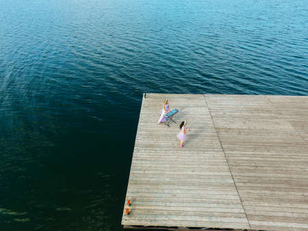 Aerial view. Two girls are sing on the pier. Surrealism.の写真素材