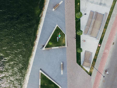 Two girls lie on a green lawn in a skate park on the embankment. Surrealism.