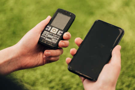 The Human Hand Picks an Old Phone That Lies Near New Smartphonesの写真素材