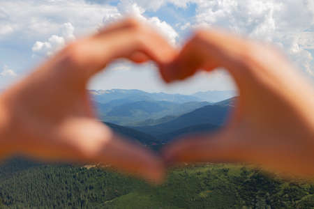 The Couple Make a Heart With Their Hands on the Background of the Skyの写真素材