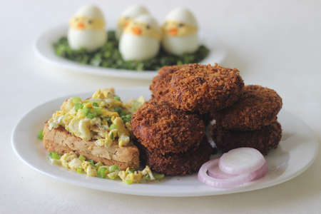 Easter day breakfast with Chicken cutlets, bread, scrambled egg and Easter eggs. Shot on white...
