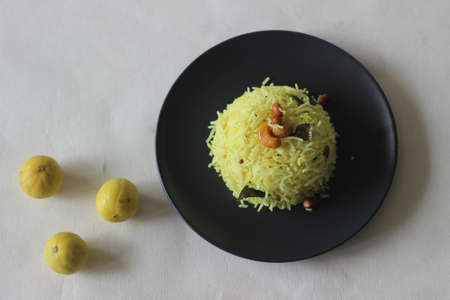 Lemon rice prepared by seasoning cooked rice with mustard seeds, fried lentils, peanuts, cashew nuts, green chillies, dry red chillies, curry leaves, asafoetida, turmeric and lime juice.の写真素材