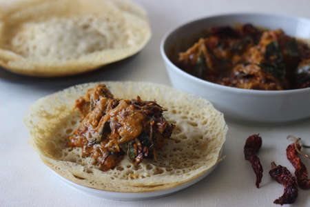 Hoppers made with foxtail millets. An experimental version of a popular Kerala dish called Appam served with Kerala style chicken curry made with home ground masala. Shot on white background.の写真素材