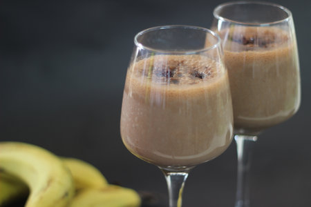 Chocolate banana milkshake made with frozen bananas, cocoa and chilled milk. Shot on black background.の写真素材