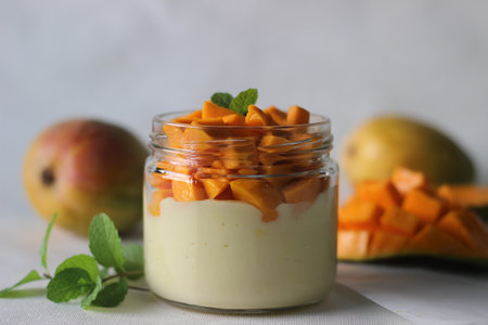 Vanilla custard topped with fresh cut mangoes served in a jar. Shot on white background.の写真素材
