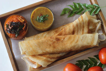 Crispy pancake made of rice and lentils. Served with tomato chilly condiment and sambar. Shot on white background.の写真素材