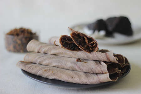 Finger millet crepes with freshly grated coconut and palm jaggery filling. Shot on white background.の写真素材